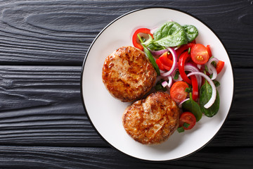 French meat balls crepinette served with fresh vegetable salad close-up. Horizontal top view