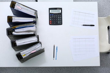 Binders with papers are waiting to be processed with bookkeeper. Internal Revenue Service inspector working place. View from above