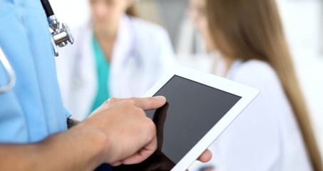 Surgeon doctor using tablet computer, close-up of hands at touch pad screen