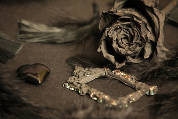 Black bird feathers, antique frame, glass heart and black rose. Gothic Valentine's Day Background....