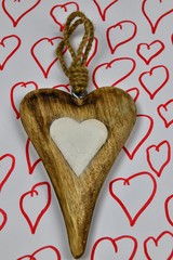A wooden Valentine heart with the white center and with a  string on the background with red...