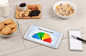 Healthy food with tablet on a wooden background with words Body Mass Index. Health concept.