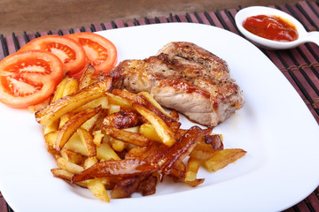 Grilled free-range beef steak with potato free, fresh tomatoes and sauce on a brown stone background