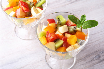 Diet-Fresh tasty mix fruit salad in the bowl on the wooden table, healthy breakfast, weight loss concept.