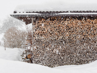 Neatly stacked firewood in snowfall in Austria
