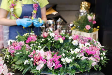 The florist creates a wreath of exotic flowers in pink tones from orchids, roses, and other flowers, herbs.