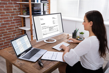 Businesswoman Checking Invoice On Computer