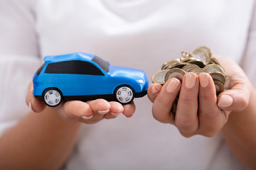 Fototapeta premium Woman Holding Blue Car And Coins