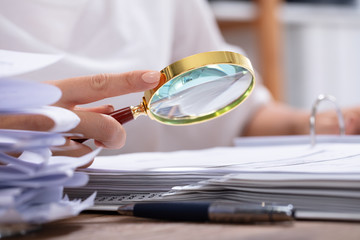 Woman Holding Magnifying Glass Over Invoice