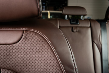 Part of red leather car seat with the unfocused car interior on the background