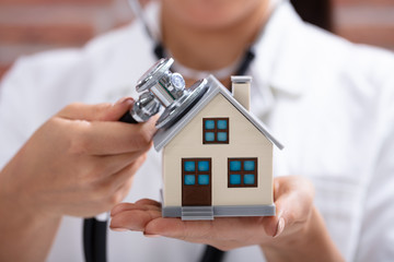 Doctor Using Stethoscope To Check Model House
