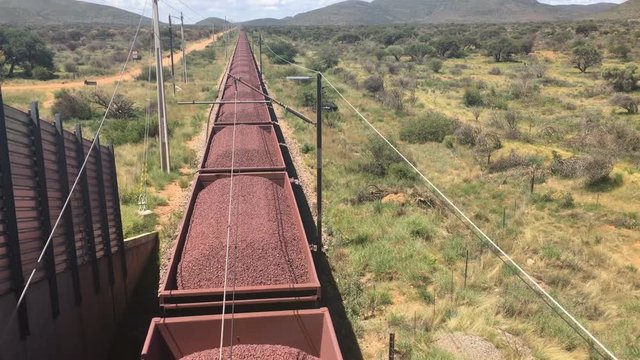 Iron ore being transported on railroad trucks by a very long freight train, South Africa
