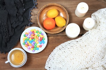Hygge autumn or winter time for tea. Flat lay with chocolate candies called lentils, candles, lemon and tangerin