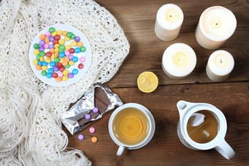 Hygge autumn or winter time for tea. Flat lay with chocolate candies called lentils, candles, lemon and tangerin