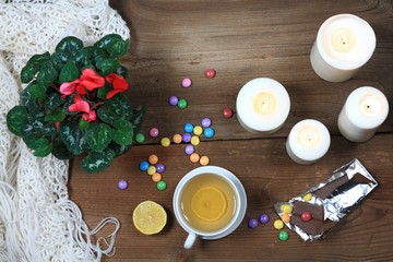 Obraz na płótnie Canvas Hygge autumn or winter time for tea. Flat lay with chocolate candies called lentils, candles, lemon and flower cyclamen