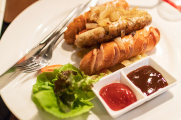 Grilled sausages serving with ketchup, barbeque sauce and organic vegetable salad. 