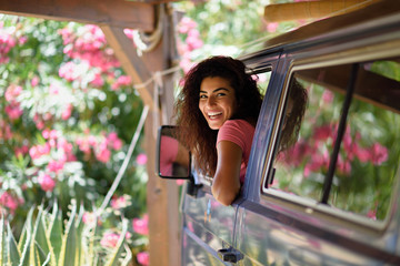 Young woman in a camper van in a beautiful camping with pink flowers