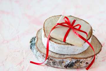 A gift with a red ribbon on a tree stand.
