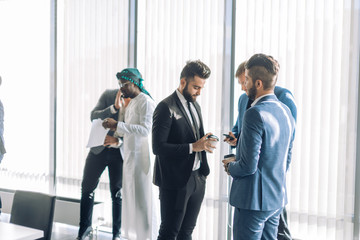 Multicultural business male team workers chatting at meeting, socializing during break at business meeting or conference
