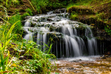 Fototapeta na wymiar Beautiful forest stream, small waterfall 