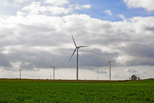 Wind turbines with green field and cloudy sky