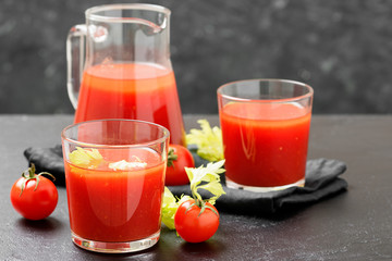 Tomato juice in glass with celery, cherry tomato  on dark background.