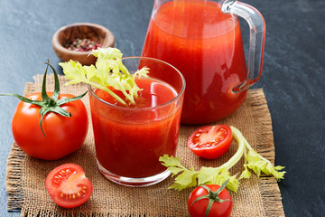 Tomato juice in glass with celery, cherry tomato  on dark background.