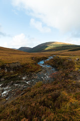 River flowing towards the valley at the Fairy Pools on Isle of Skye during a cloud-covered autumn day (Isle of Skye, Scotland, United Kingdom, Europe)