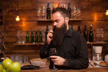 Bearded young batender talking on the phone taking care of his business. Hipster pub.