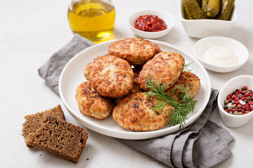 Juicy delicious meat cutlets in a white plate on a light gray table. 