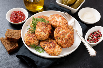 Juicy delicious meat cutlets in a white plate on a black stone table. 
