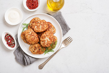 Juicy delicious meat cutlets in a white plate on a light gray table. Top view 