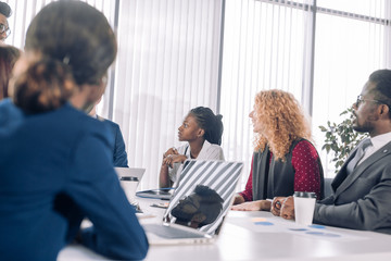 Multiracial business coworkers talking, interacting on workplaces, business communication concept