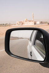 Rear-view mirror showing the deserted street and in the background a mosque