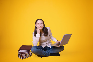 Young female student sitting with crossed legs working with a laptop, young student life