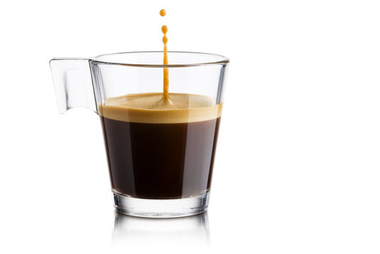 Fototapeta Czarna kawa w szklanej filiżance z doskakiwanie kroplą na białym tle