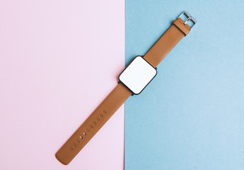 Smart Accessories, smartwatch on pink blue table. Flat lay, top view.