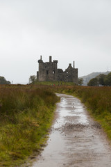 Fototapeta na wymiar Close-up of the ruins of Kilchurn Castle near Loch Lomond during a rainy autumn day with path to castle (Scotland, United Kingdom, Europe)