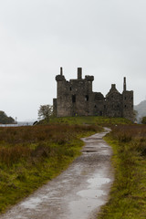 Fototapeta na wymiar Close-up of the ruins of Kilchurn Castle near Loch Lomond during a rainy autumn day with path to castle (Scotland, United Kingdom, Europe)