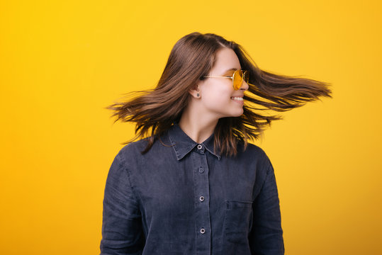 Portrait of a happy young woman spinning her head isolated over yellow background.