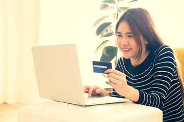 Young asian women holding credit card on hand for online shopping with laptop computer in the room at home. Teenager buying sale products  on internet concept. Vintage retro color style