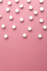 image of white pills on pink bacFkground. Copy space. Flat lay. vertical composition.