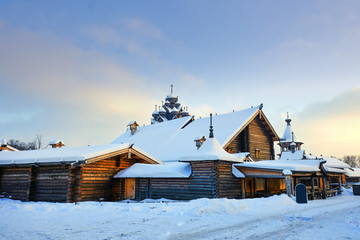 Traditional Russian village with wooden houses and a church, the Bogoslovka manor, in the city of St. Petersburg on a winter evening