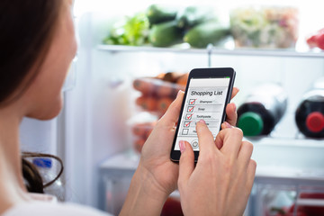 Woman Marking Shopping List On Mobile Phone