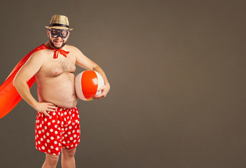 Funny fat man in a super hero costume on the beach a background for text.