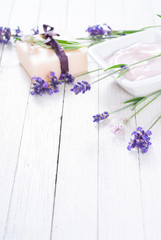 pink moisturizer cream, soap bar and purple lavender flowers on white rusty wooden table background