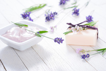 Obraz na płótnie Canvas pink moisturizer cream, soap bar and purple lavender flowers on white rusty wooden table background