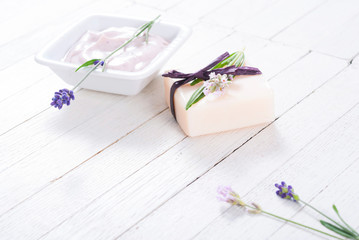 pink moisturizer cream, soap bar and purple lavender flowers on white rusty wooden table background