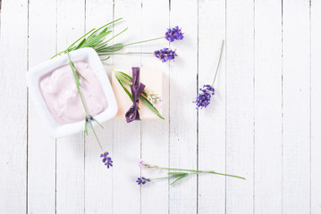 pink moisturizer cream, soap bar and purple lavender flowers on white rusty wooden table background
