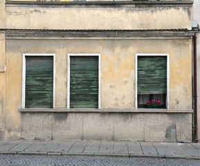 Fototapeta na wymiar three windows with shutters broken of an old house with a case o